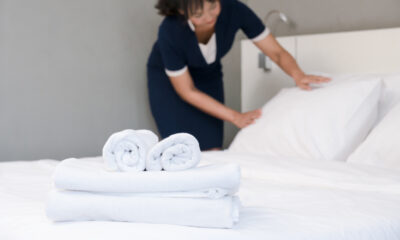 Hotel room service. Maid making bed in a room, focus of clean towels